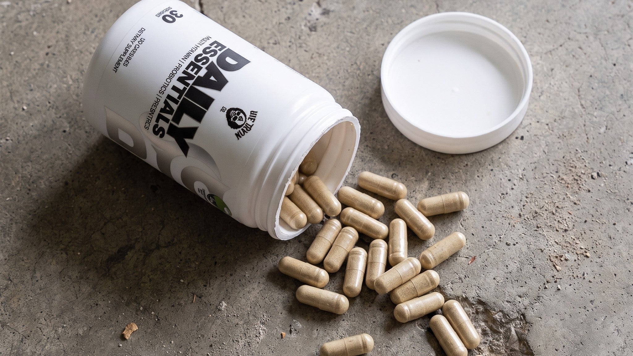 Daily Essentials tub on concrete with chelated multivitamin capsules spilling out