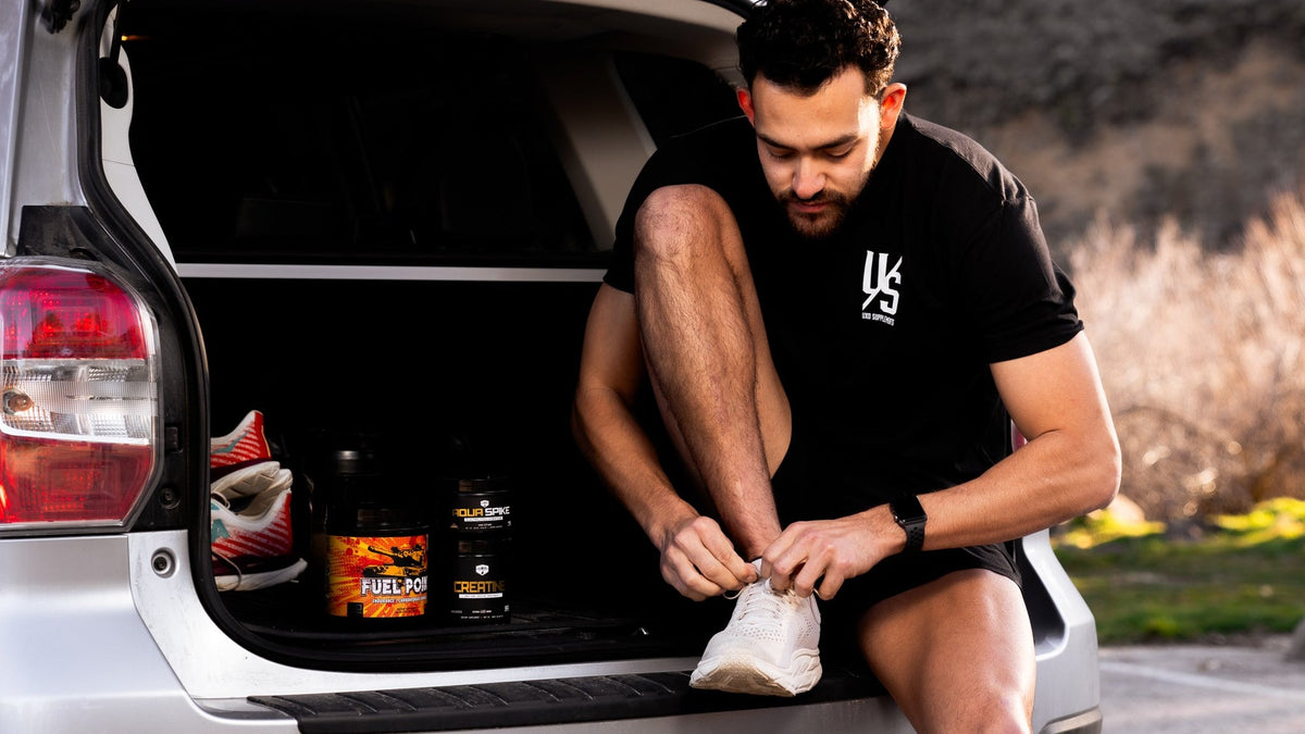Runner lacing his shoes at the car trunk with Fuel Point and supplements packed