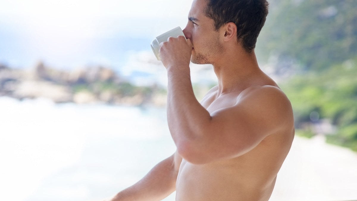 Man drinking his morning coffee on a balcony overlooking the water