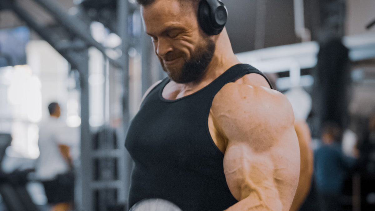 Lifter in headphones mid dumbbell curl in a commercial gym