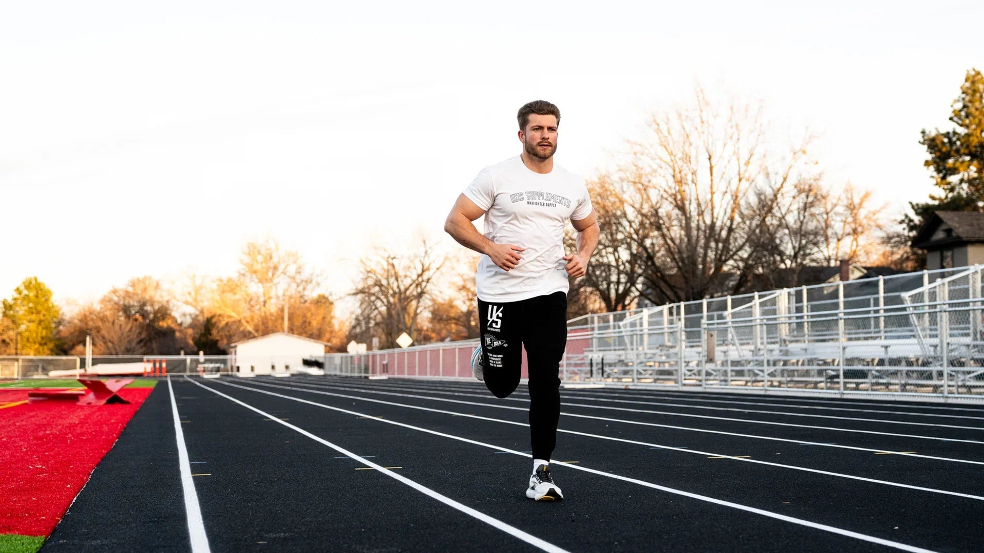 Hybrid athlete running on an outdoor track at sunrise