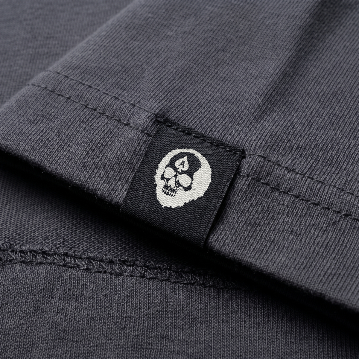 Woven Die Tryin Co. skull label stitched to the hem of an oversized tee