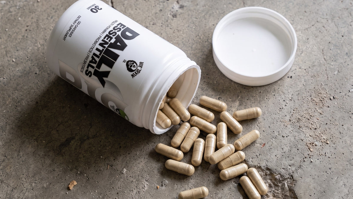 Daily Essentials tub on concrete with chelated multivitamin capsules spilling out