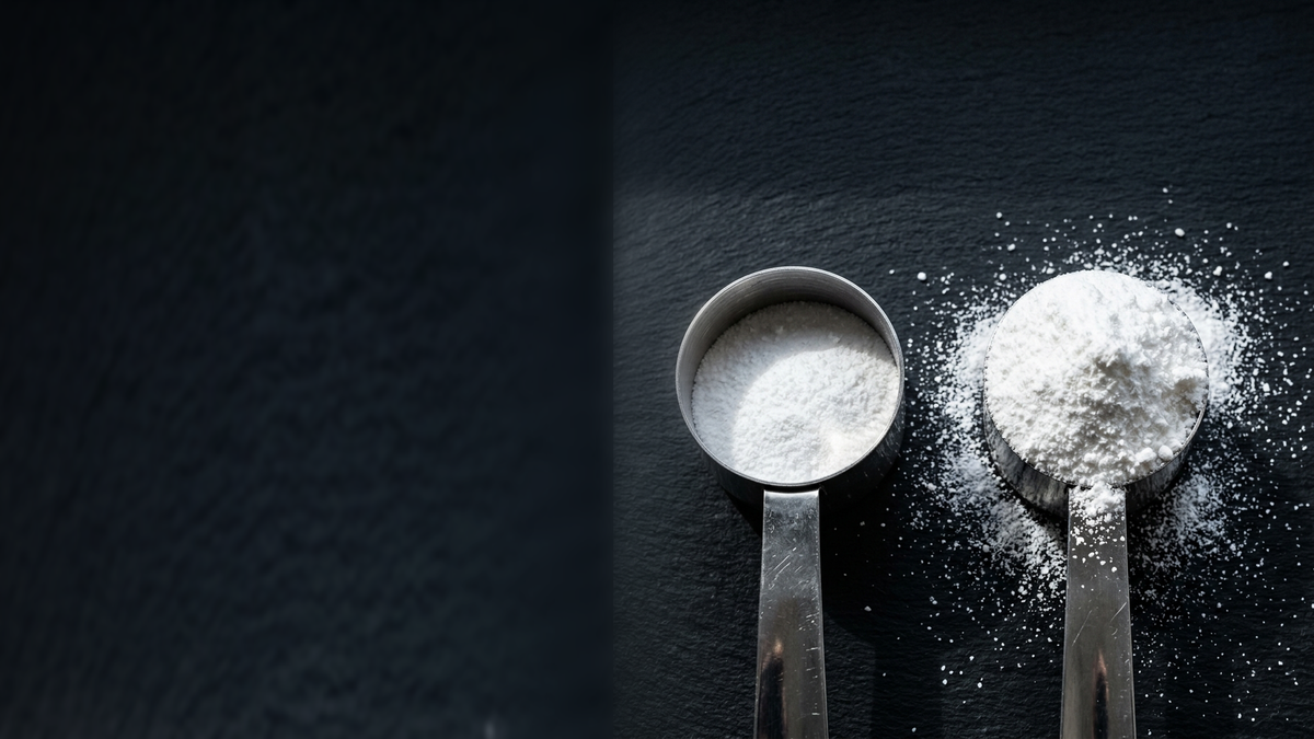 Two steel scoops of white powder on slate, the left only part full, the right heaped and spilling