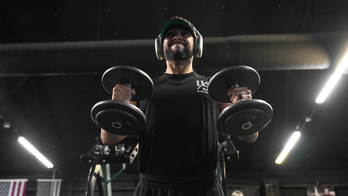 Lifter finishing a set of standing dumbbell curls in a gym