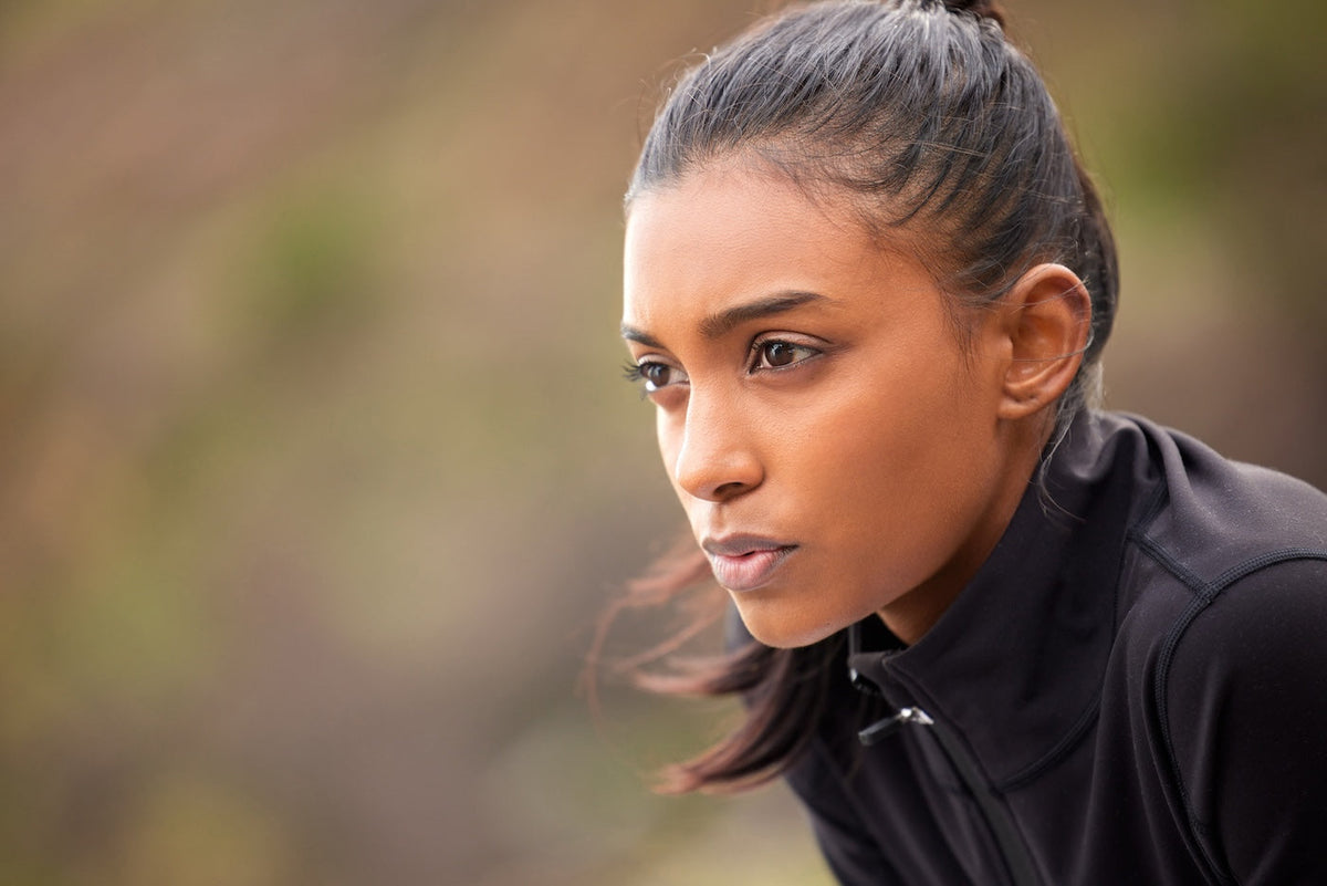Focused female athlete outdoors before a session, mentally rehearsing the work ahead