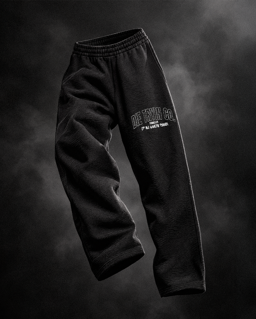Black straight-leg joggers with a Die Tryin Co. thigh print floating against a dark smoky backdrop