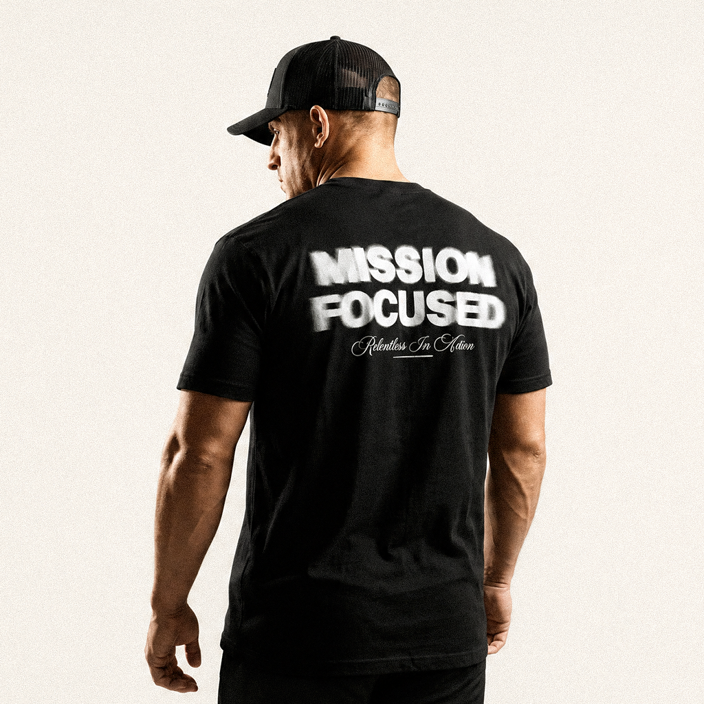 Back view of a man in a black cap wearing a black tee with a blurred Mission Focused back print
