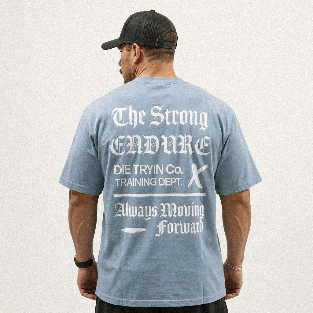Back view of a man in a black cap wearing a light blue oversized tee with a white Training Dept. print