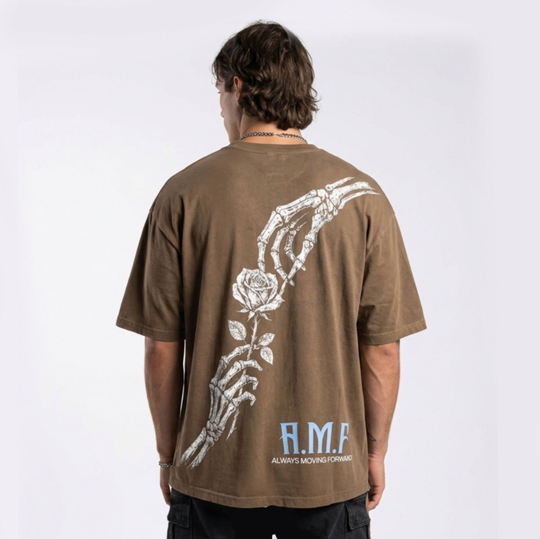 Back of the Beauty In Progress oversized tee in brown with skeleton hand and rose graphic