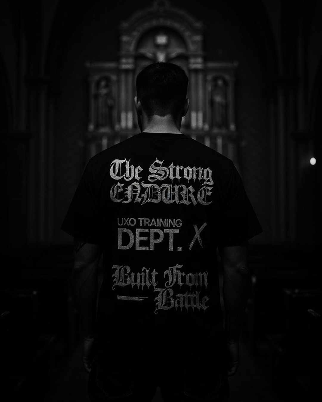 Back of the Training Dept tee reading The Strong Endure, in black